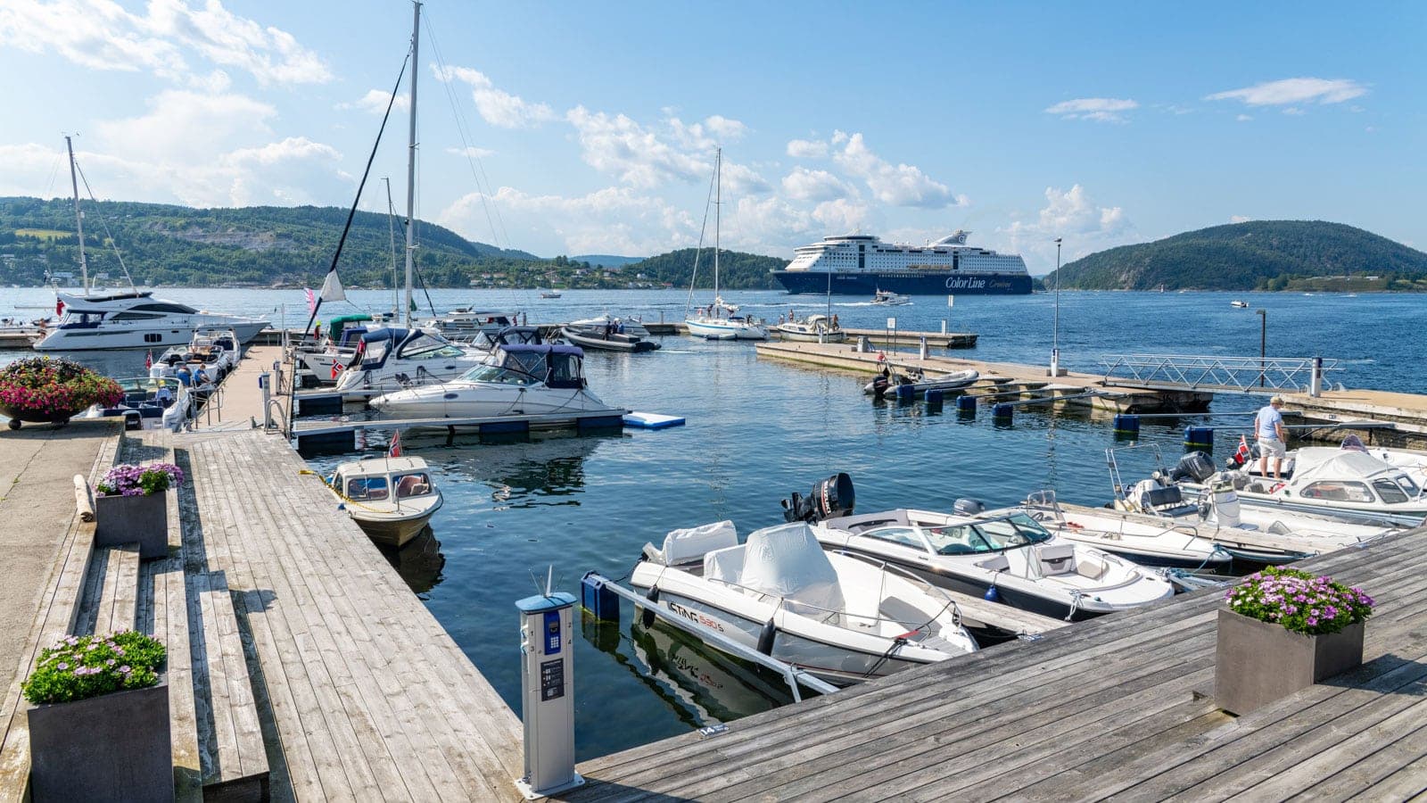 Båter i en gjestehavn med en større cruisebåt som seiler forbi i Oslofjorden
