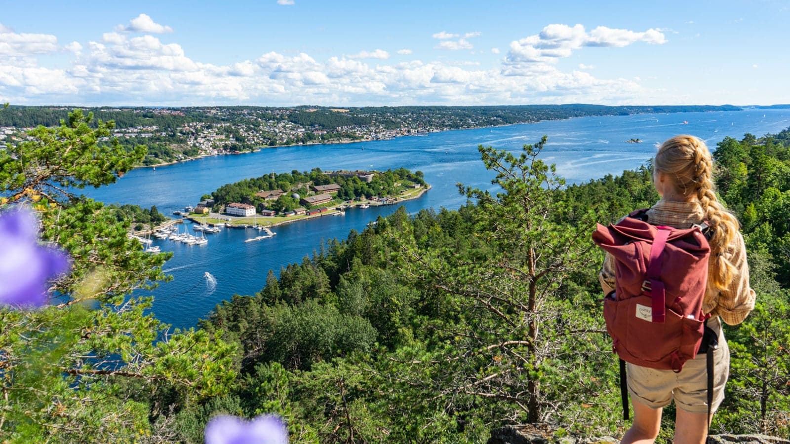 Jente som står på utsiktspunkt og ser over Oslofjorden en sommerdag