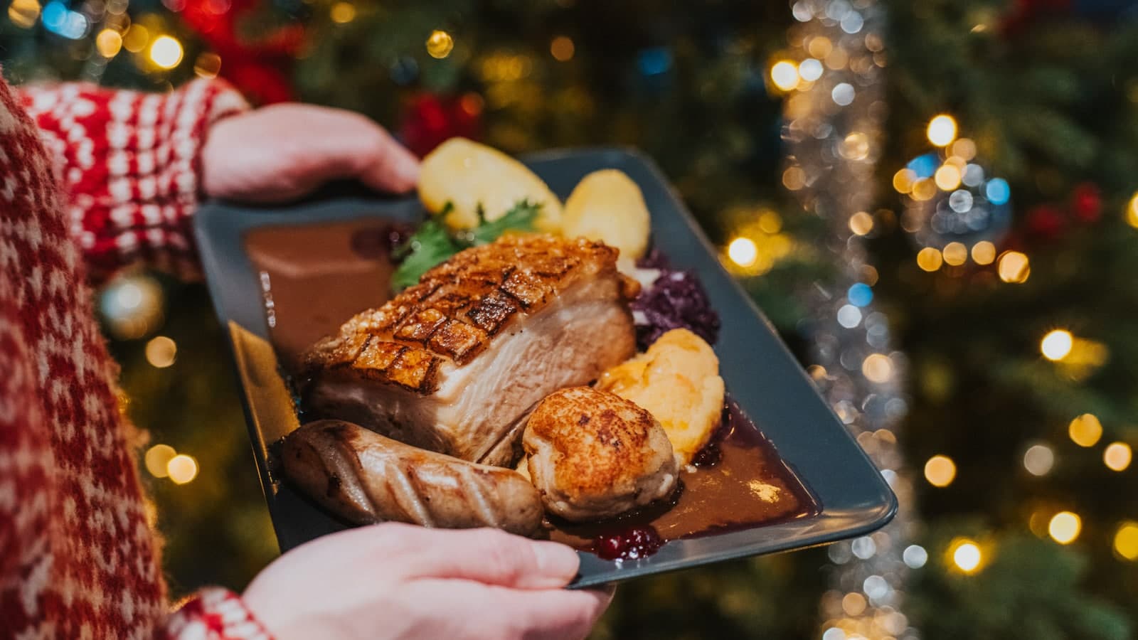 Juletallerken som holdes foran et juletre