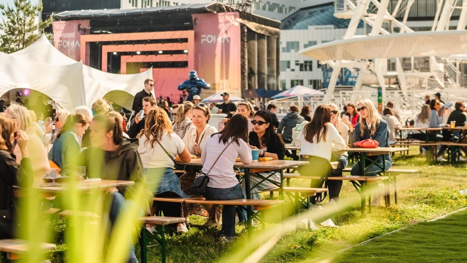 mennesker som sitter og spise på langbord på en festival