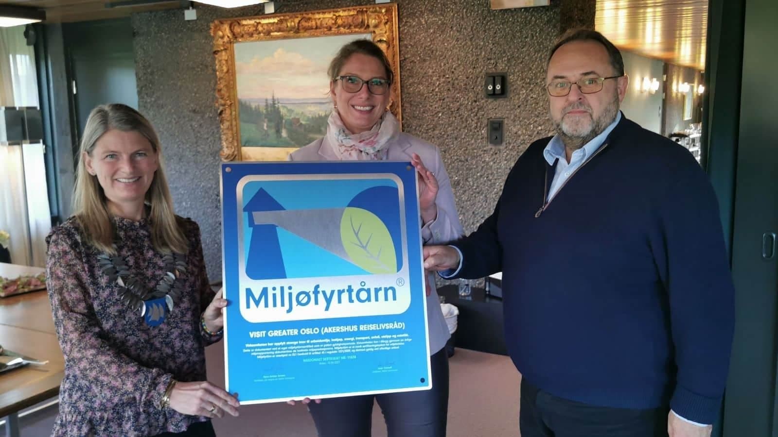 to damer og en mann med et miljøfyrtårn mellom seg