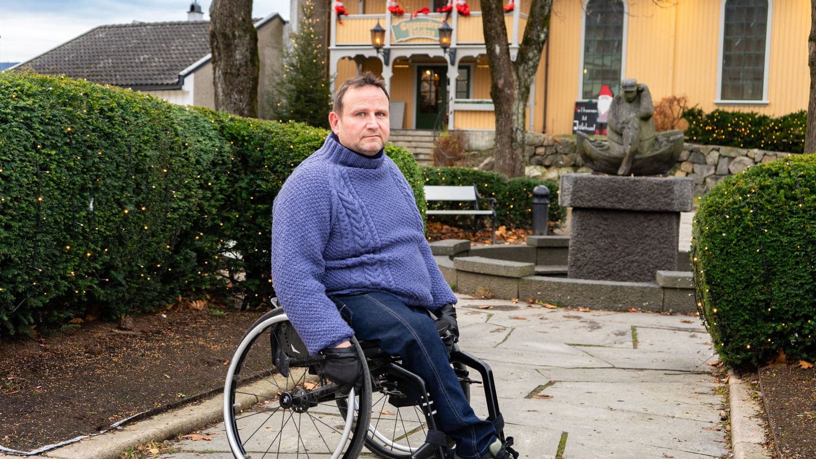 Rullestolbruker utenfor gult trehus