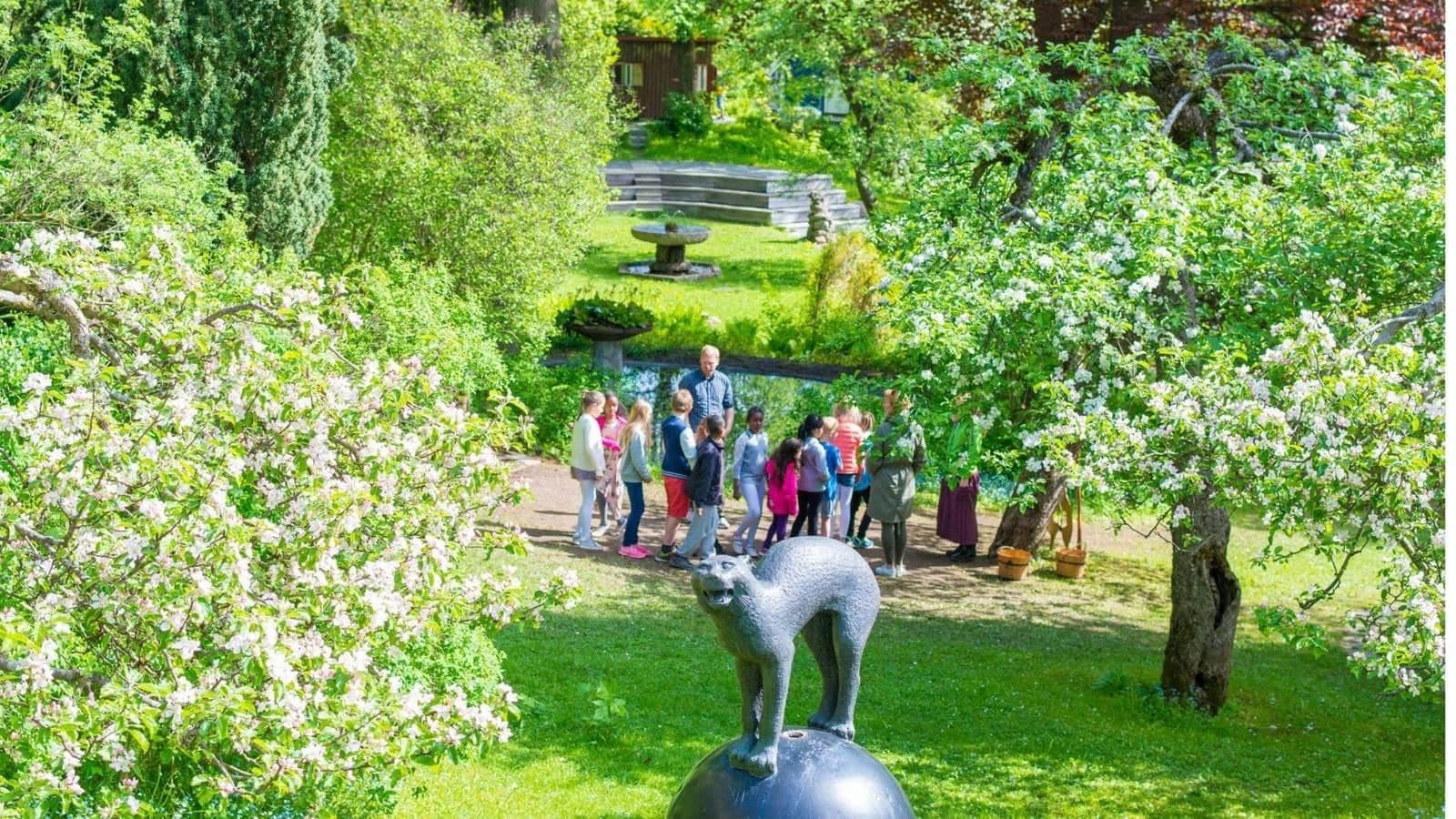 statue i en park med mange mennesker som står under noen trær